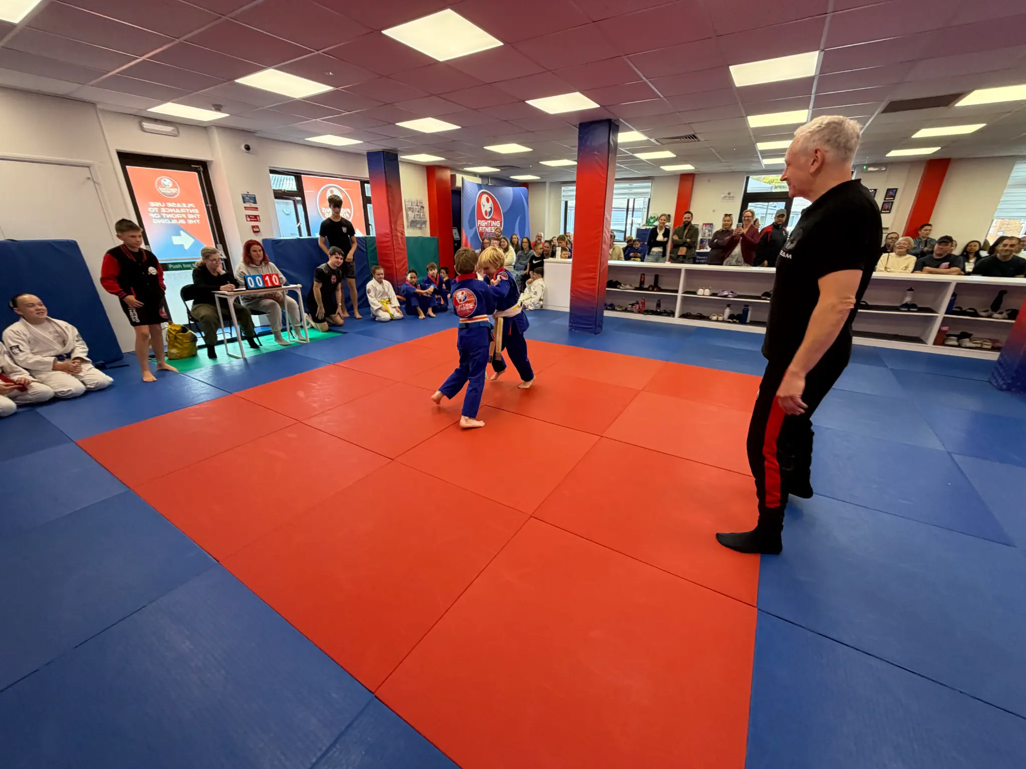 A young judoka competing with a referee supervising safely