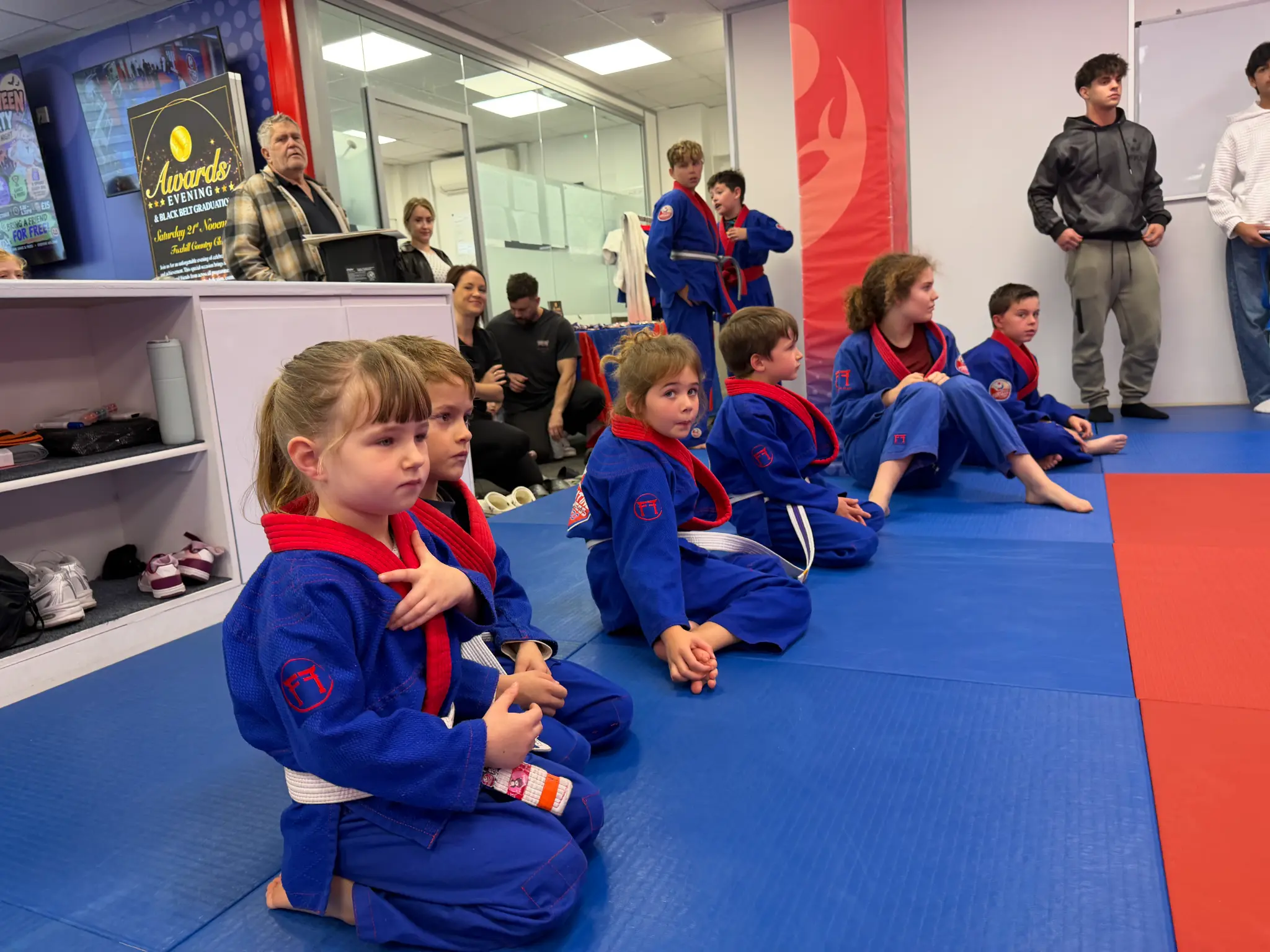 Young team members watching from the edge of the judo mat